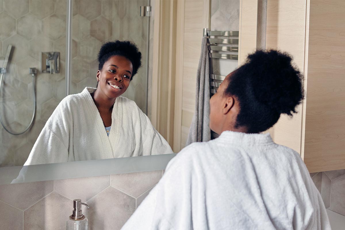 Woman with nice clear skin smiling into mirror